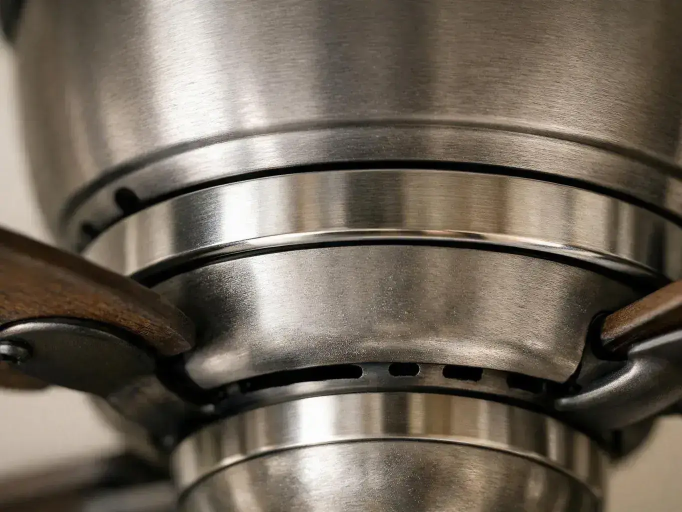 Close-up of a brushed metal gas stove burner with dark pan supports and vent slots